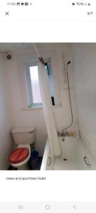 a bathroom with a toilet and a bath tub with a window at Cosy room in thornton heath in Thornton Heath