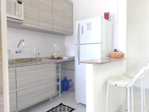 Apartamento a 100 metros da Praia في بيرتيوغا: مطبخ أبيض مع ثلاجة بيضاء ومقعد