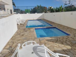 Apartamento a 100 metros da Praia في بيرتيوغا: مسبح مع كراسي وطاولة
