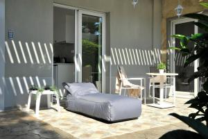 a bed on a patio with a table and chairs at Alekos Luxury Suites - Free 24hr Transformation From To Airport in Artemida