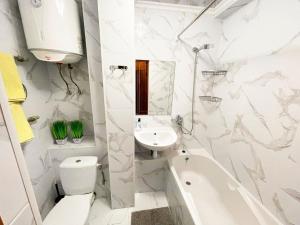 a white bathroom with a sink and a toilet and a tub at ARTAL Apartment Yordanska Street 22 in Kyiv +7 photos