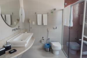 a white bathroom with a sink and a toilet at Ibituruna Center Hotel in Governador Valadares