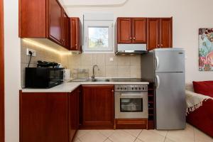 Una cocina con gabinetes de madera y un refrigerador de acero inoxidable. en Villa Panorama, en Skala Potamias