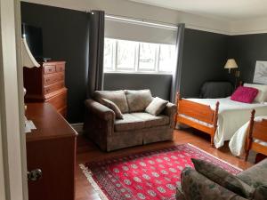 a bedroom with a bed and a couch and a chair at B&B Aux Deux Pignons in Donnacona
