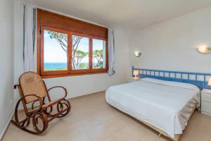 a bedroom with a bed and a window and a chair at E-2 CALELLA DE PALAFRUGELL 8 PAX in Calella de Palafrugell