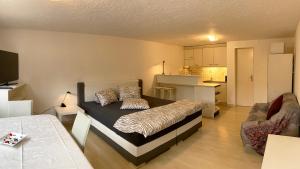 ein Schlafzimmer mit einem Bett und eine Küche in einem Zimmer in der Unterkunft Les Ouches in Saint-Blaise