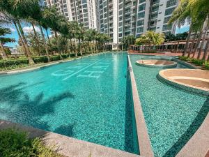 a large swimming pool with palm trees and buildings at [Starry Homes @ Green Haven] 2Beds 2Bath+Pool View in Masai