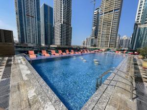 a large swimming pool with lounge chairs in a city at VayK - Stylish One Bedroom near Marina with Full Lake View in Dubai