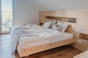 a wooden bed with white sheets and pillows at Janina's Dragonfly house in Nova Vas