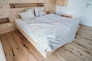 Cette chambre comprend un grand lit blanc et du parquet. dans l'établissement Janina's Dragonfly house, à Nova Vas