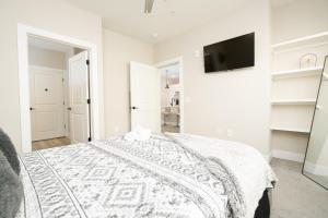 a white bedroom with a bed and a flat screen tv at Atlanta’s Summerhill Stay in Atlanta
