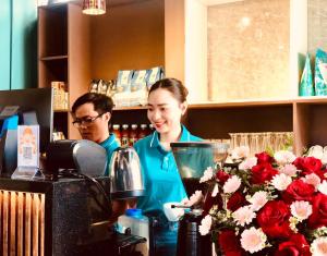 PUPON Homestay and Coffee في كوانج نجاي: امرأة تقف عند كونتر في مقهى