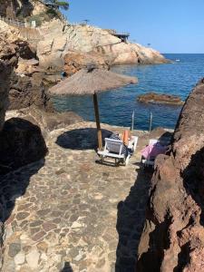 Cap Sa Sal Aquamarina Begur في بيغور: شاطئ فيه كرسيين ومظله