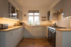 cocina con armarios blancos, fregadero y fogones en Rie's Retreat- The Gold Room, en Glastonbury