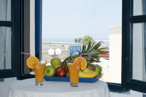 uma mesa com dois copos de sumo e uma taça de fruta em Athina Apartments Naxos Town em Naxos Chora