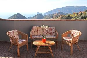 3 Stühle und ein Tisch mit einer Vase Blumen auf dem Balkon in der Unterkunft Vida Noa - Casa vista mare - Sud Sardegna in Nebida