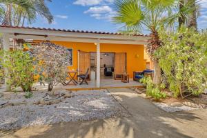 een geel huis met een patio en palmbomen bij Tropical Divers Resort in Kralendijk