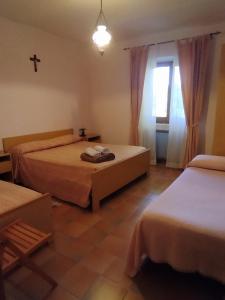 a bedroom with two beds and a cross on the wall at Agriturismo Masseria Testa Ciruglio in Ielsi