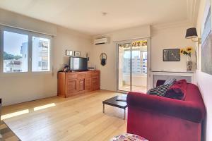 een woonkamer met een rode bank en een tv bij Beautiful 3 room apartment with air-conditioned loggia close to the Croiset in Cannes