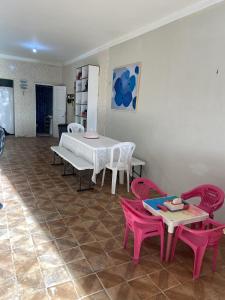 ein Esszimmer mit rosa Stühlen, einem Tisch, einem Tisch und Stühlen in der Unterkunft Casinha Valdenia: No paraíso com Wi-Fi, em Mundaú in Trairi