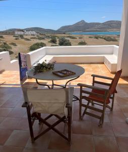 a table and chairs on a patio with a view of the ocean at Vintage lover's getaway in Andiparos