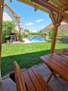 a wooden table and chairs on a patio with a yard at Landhaus Forrás in Balatonfüred