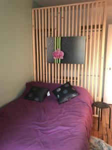 a purple bed with two pillows and a flower on it at Appart douillet Paris 11 in Paris