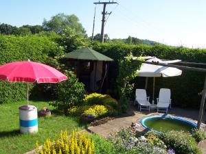 a garden with a hot tub and an umbrella and chairs at FeWo Ruppel in Driedorf