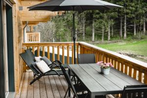 einem Holztisch mit einem Sonnenschirm auf dem Deck in der Unterkunft Chalet 49 Nesselgraben - Ferienwohnungen aus Holz in Koppl