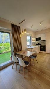 a dining room with a table and chairs and a kitchen at Green Terrace Big Family Apartment in Wrocław