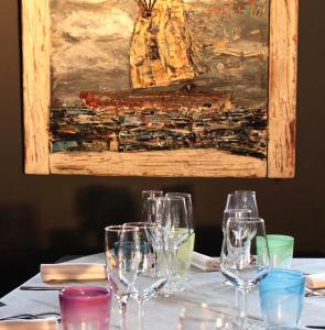 una mesa con copas de vino con una pintura en Ca’Bosello Ristorante e locanda, 