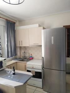 a kitchen with a stainless steel refrigerator and white cabinets at Adorable Apartment in the center in Volos