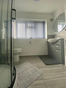 uma casa de banho com um chuveiro, um lavatório e um WC. em Gatwick Deluxe En-suite Rooms em Horley