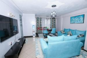 sala de estar con sofá azul y TV en Atlantic House 3 Bedroom, Naivasha, en Naivasha