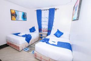 two beds in a room with blue curtains at Atlantic House 3 Bedroom, Naivasha in Naivasha