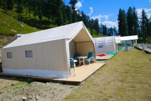 Valhalla Resort Kumrat في Tāl: خيمة بيضاء كبيرة مع طاولة وكراسي