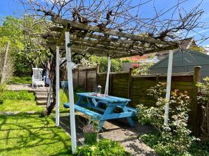 a blue picnic table under a pergola in a garden at Rie's Retreat - The Emerald room in Glastonbury