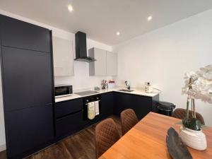 een keuken met een tafel en een zwarte koelkast bij Star London Finchley Road 3-Bed Escape with Garden in Londen
