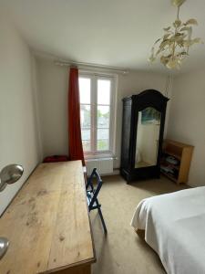 um quarto com uma mesa de madeira, uma cama e uma janela em Chambres à louer centre-ville em Le Mans