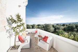 a balcony with white furniture and red pillows at Masseria Alchimia in Fasano