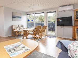 een woonkamer met een tafel en stoelen en een televisie bij 4 person holiday home in L kken in Løkken