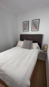 een slaapkamer met een wit bed met twee foto's aan de muur bij Rockside Residentes Suites La Línea N5 in La Línea de la Concepción