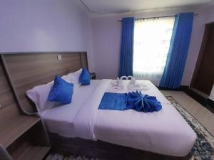 a bedroom with a large white bed with blue pillows at Gamtoos House:Lovely 3 Bedroom House in Naivasha