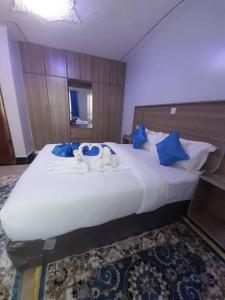 a bedroom with a large white bed with blue pillows at Gamtoos House:Lovely 3 Bedroom House in Naivasha