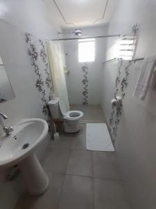 a white bathroom with a toilet and a sink at Gamtoos House:Lovely 3 Bedroom House in Naivasha