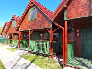 una fila de casas con puertas verdes y techo rojo en Słoneczny Zakątek, en Sztutowo