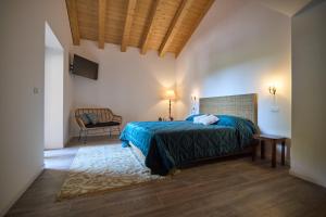 ein Schlafzimmer mit einem Bett und einem Stuhl in einem Zimmer in der Unterkunft Casale San Pietro in Palmanova