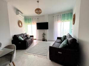 a living room with two couches and a flat screen tv at O mar na frente de lux Caparica in Costa da Caparica