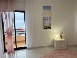 a white room with a window and a table with a candle at O mar na frente de lux Caparica in Costa da Caparica