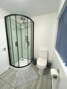 a bathroom with a toilet and a glass shower at Gatwick Deluxe En-suite Rooms in Horley